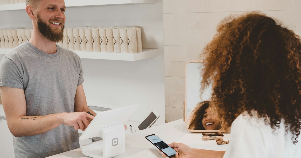 Shopkeeper processing a card payment on a modern point-of-sale terminal